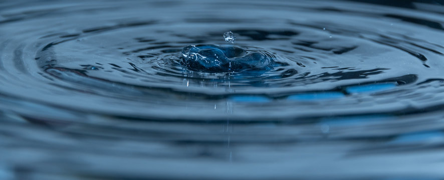 Wassertropfen prasselt in das blaue Wasser mit wellen - Wasserhintergrund