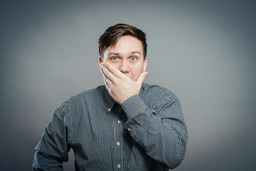 Emotional man keep his mouth closed by his hands