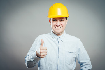 Portrait of smiling handyman with tools and paper showing thumbs up sign   isolated on  white background