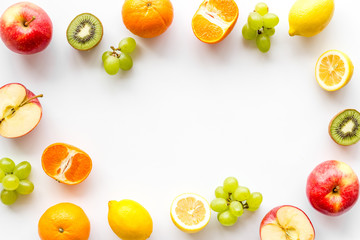Oranges, lemon, apple, kiwi and grape - healthy food concept with fruits - on white background top-down frame copy space