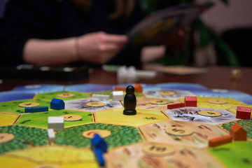 Friend are playing board game in the evening. 