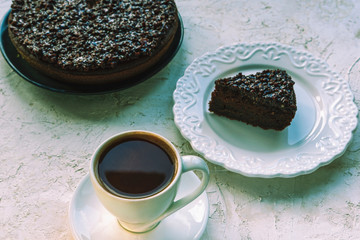 Coffee in white cup and chocolate cake on white table