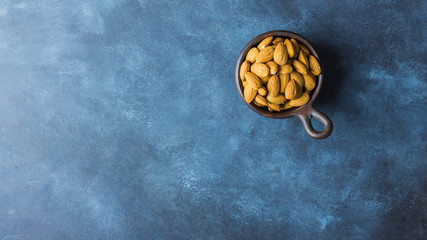 Almonds on a clay pot with nice blue background. Top view. Copy space. Healthy food concept 