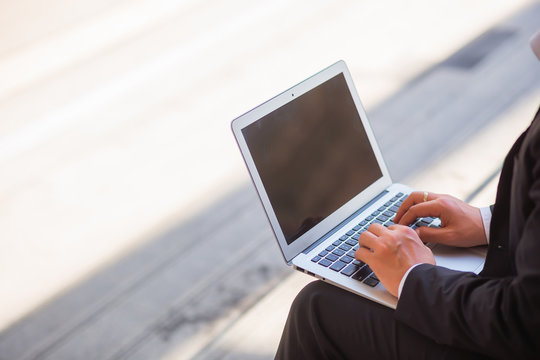 People are sitting at a table and using the laptop outside in the outdoors. Concept of using technology to communicate and can work anywhere, anytime
