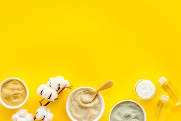 Various kinds of cosmetic clay on yellow desk top view copy space
