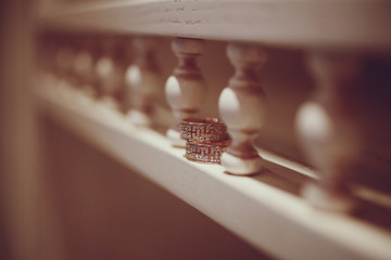 Luxury stylish gold wedding rings on white wooden furniture. Close-up shot