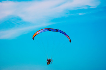 Aircraft parachute with a motor. Man with paraglider fly in the blue sky.