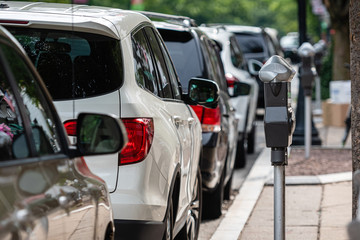 a row of parked cars on the side of the street and a parking payment machine