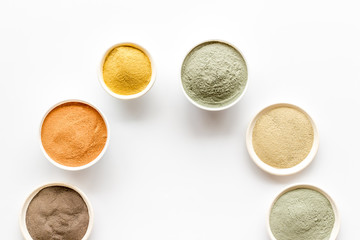 Yellow, red, white, blue and black cosmetic clay on white table top view copy space