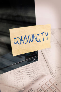 Writing note showing Community. Business concept for group of showing with a common characteristics living together Notation paper computer monitor screen near white keyboard