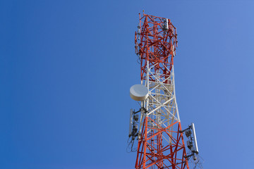 Mobile phone communication antenna tower with satellite dish on blue sky background