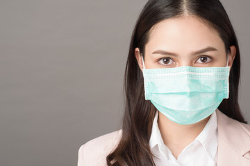 close up portrait of business woman with surgical mask on gray background