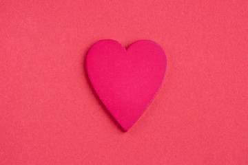 On mother's Day, a red wooden heart lies on a pink background. Valentine's day, March 8, minimal concept. Greeting card with a heart on the background. The view from the top