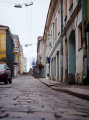 Fototapeta na wymiar Vyborg, Russia, Leningrad Region - 17.01.2020: Historical city Center. Medieval narrow paved street with Old Finnish buildings and houses in the morning fog in early spring