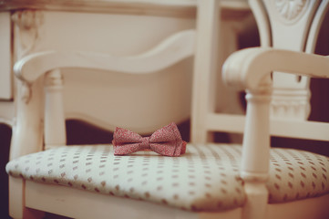 A pink bow tie is on top of a chair in classics style
