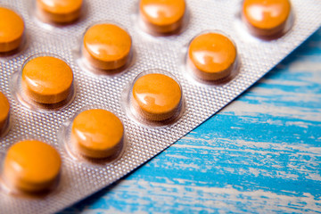 A package of orange tablets is placed on a blue background