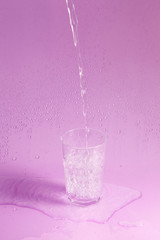 Naklejka na ściany i meble splashing clean water in glass on pastel background