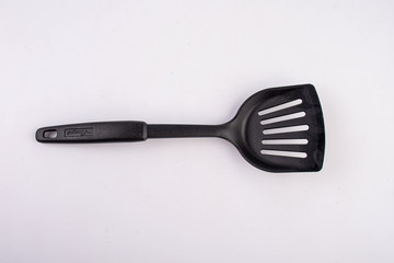 Plastic black spatula for a frying pan isolated on white background. New spatula. Spatula for cook food