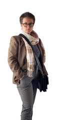 Fototapeta premium A woman with a short haircut, in a light jacket and with a light scarf around her neck, with a bag posing on a white background in the studio. Copy space.