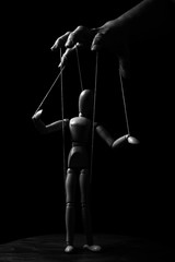 Conceptual image of a hand with strings to control a marionette in monochrome - 339815245