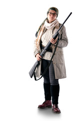 A full-length woman in a light coat, with a scarf on her head, with a gun in her hands and a bandoleer on her belt, poses on a white background. The woman is a hunter.