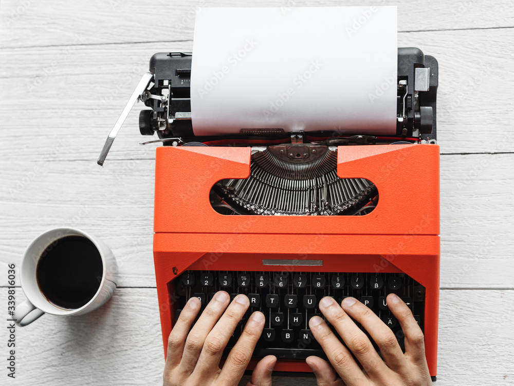 Fototapete aerial view of a man typing on a retro typewriter blank paper