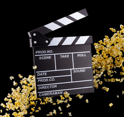 Flying popcorn and film clapper board isolated on black background