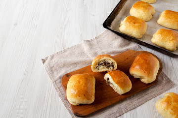Home-baked Beef Russian Bierocks on a rustic wooden board on a white wooden background, side view. Copy space.