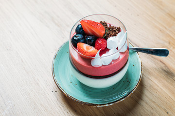 traditional sweet panacotta with berries and strawberries in a glass cup