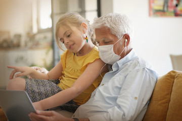 Obraz premium Man with child at home connected on laptop during COVID19 pandemic