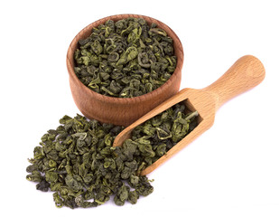 Dried green tea in a wooden bowl, with a scoop delicious, natural