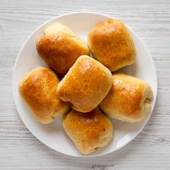 Home-baked Beef Russian Bierocks on a white plate on a white wooden table, top view. Flat lay, overhead, from above.