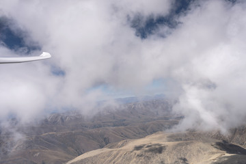 flying among cloud wisps, above st. Bathans range, New Zealand