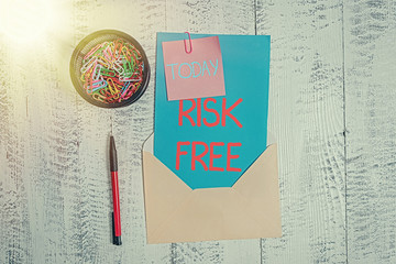 Conceptual hand writing showing Risk Free. Concept meaning used to describe something that does not involve any danger Envelope letter sticky note ballpoint clips on wooden background