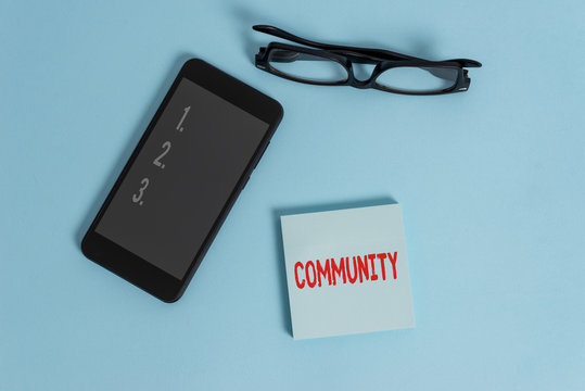 Word writing text Community. Business photo showcasing group of showing with a common characteristics living together Dark eyeglasses colored sticky note smartphone fashion pastel background