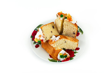 Sliced Easter cake poured with fondant and candied fruit on a white background