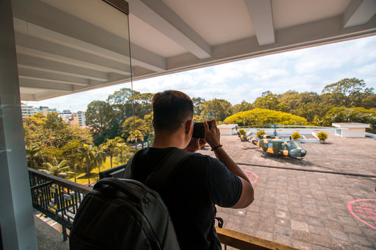 Back side of Young Asian traveling men taking a photo of Independence Palace in Ho Chi Minh City, Vietnam.  Independence Palace is known as Reunification Palace and was built in 1962-1966. 