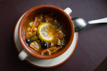 Ceramic plate with soup solyanka, russian hodgepodge soup with olives and lemon
