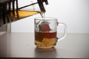 A teapot with tea is poured into a mug