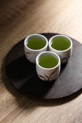 Japanese green tea in ceramic cup on wooden tray
