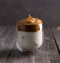 Keto dalgona whipped coffee with milk in a glass on rustic wooden background