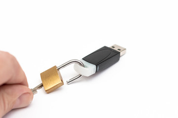 A hand with a key opens the lock on a flash drive. Information hacking concept. Close-up. White...