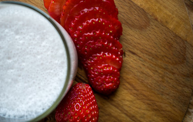 Strawberry smoothie with milk and some strawberries on wooden background, close up