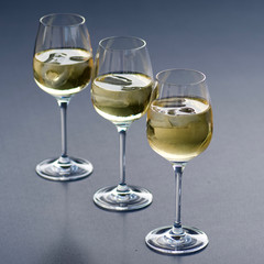 three glasses of fresh golden delicious riesling white wine in a line