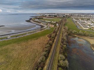 Aerial view on rail road to Galway city, Ballyloughane Beach on the left. Cloudy sky.