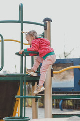 A child on the Playground with a cute face on a natural background. A little girl with blond hair pulled back in ponytails. Beauty, dexterity, hairstyle. The concept of a happy childhood.