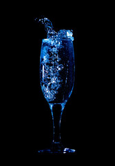 Splashes and drops of water in a glass are isolated on a black background.
