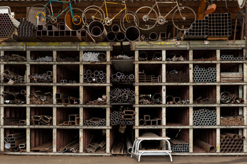 Different styles and sizes of old recycled metal pipes and profiles construction materials laying on a shelf rack in a storage. Recycled metal pieces, circular economy principle