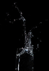 Fototapeta na wymiar Splashes and drops of water in a glass are isolated on a black .