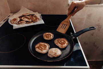 process of cooking home-made pancakes in a pan. Delicious fried pancakes for breakfast before work. female hand flips pancakes with a wooden spatula